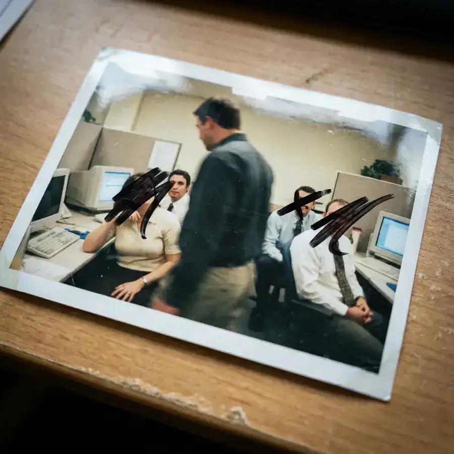 Een teamfoto op een bureau; meerdere gezichten zijn met zwarte stift doorgestreept